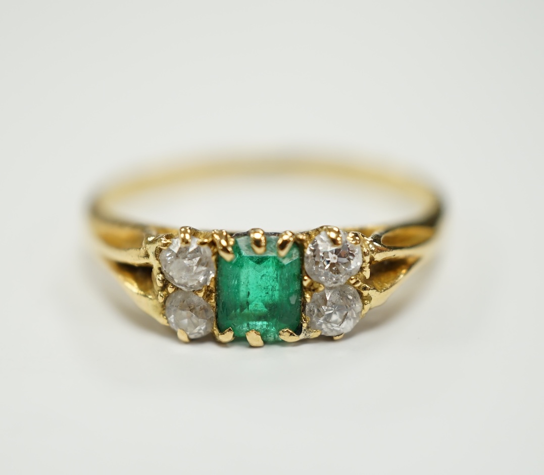 An 18ct, single stone emerald and four stone diamond cluster set ring, size M, gross weight 2.2 grams.